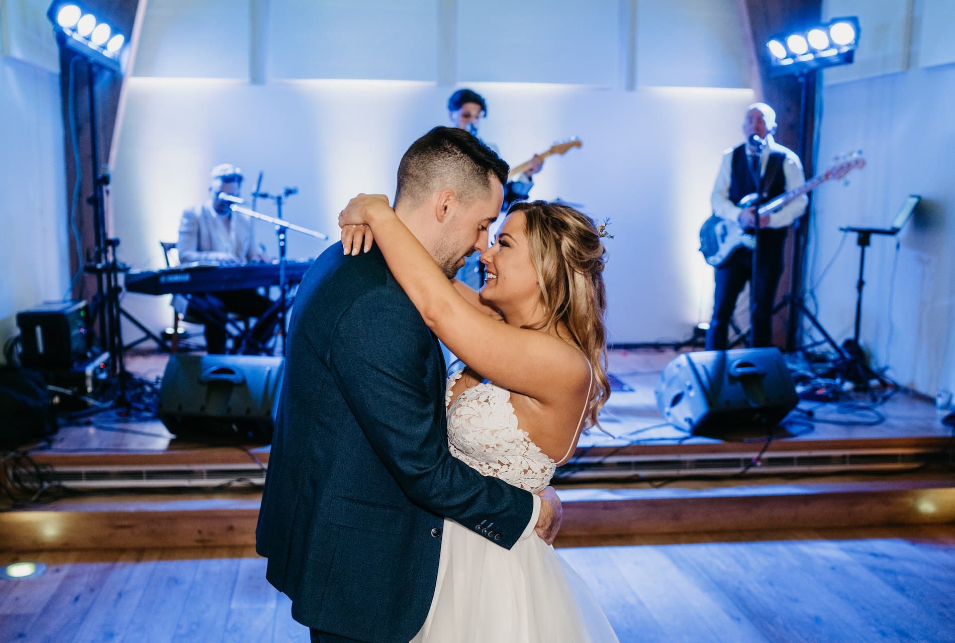 Kerry and James's first dance, foreheads together, with Miami Beat playing on the stage behind them